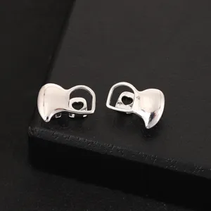 Detail shot of silver hip-hop grillz tooth caps with hollow heart design, cool streetwear style.