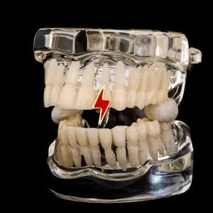 Close up detail of trendy hip hop red and gold lightning tooth grillz accessory on clear model