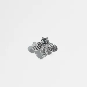 Detailed shot of a silver bee design hip-hop single tooth grillz with sparkling zircons.