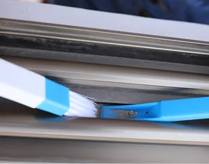 Detail shot of blue and white window track cleaning brush effectively clearing dust from gaps.