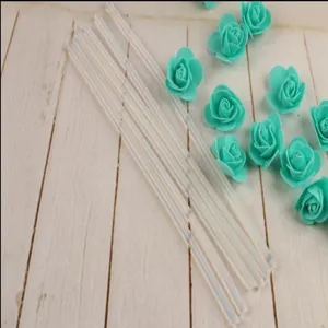 Detail shot of transparent hot melt glue sticks decorated with mint green foam roses on wood.