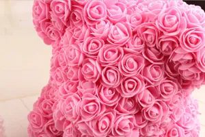 Pink foam rose bear detail close-up, handmade artificial flower gift decoration texture.