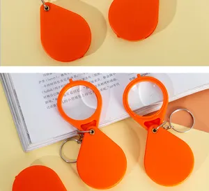 Detalle de llavero con lupa plegable portátil, lente de bolsillo naranja compacta para lectura.