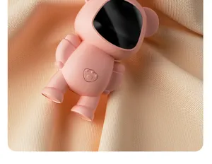 Close-up detail of the portable pink cartoon hand warmer on textured orange fabric surface.