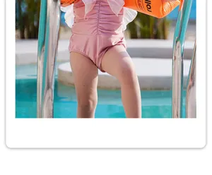 Vista dettagliata di braccioli da nuoto per bambini e costume rosa vicino alla piscina.
