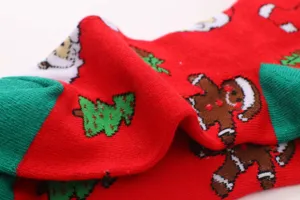 Close-up detail shot of red Christmas knit socks with festive Santa and tree patterns.