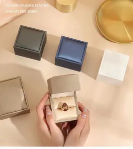 Brushed leather jewelry boxes with opened ring case showing drop gemstone ring.