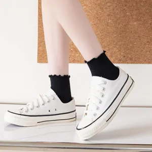 Japanische schwarze Rüschen-Kurzsocken kombiniert mit klassischen weißen Damen-Leinenschuhen.