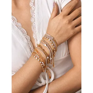 Detail shot of stacked gold-tone zirconia tennis bracelets worn on wrist, elegant and sparkling.