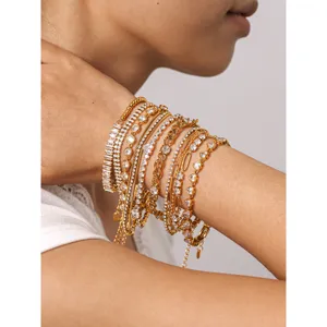 Close-up detail of stacked gold stainless steel tennis bracelets with sparkly cubic zirconia.
