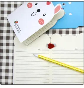 Dettaglio di mini quaderno carino con pagine rigate, copertina d'orso e cancelleria.