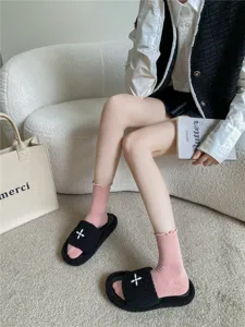 Schicke rosa Socken mit Rüschen kombiniert mit flauschigen schwarzen Hausschuhen im Alltag.