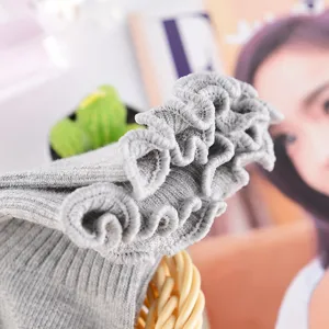 Nahaufnahme von grauen Stricksocken mit Rüschenrand und feiner Rippenstruktur.