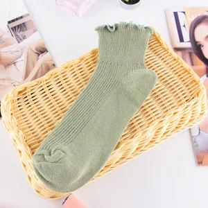 Nahaufnahme von hellgrünen Rüschen-Socken, die feine Strickstruktur und Details zeigen.