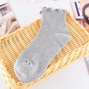 Nahaufnahme grauer Strickkurzsocken mit süßem Rüschensaum und feiner Rippenstruktur.
