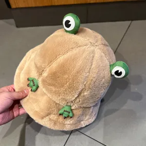 Detailed view of fluffy khaki plush frog bucket hat, featuring cute 3D eyes and paws, warm winter.