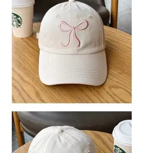 Close-up detail of the cute beige baseball cap featuring a sweet pink embroidered bow.