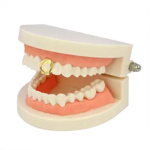 Dettaglio in primo piano di un grillz per denti a cuore cavo placcato oro gioiello dentale.