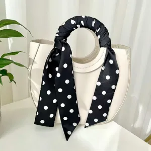 Foulard sottile a pois bianco e nero legato al manico della borsa, accessorio chic.