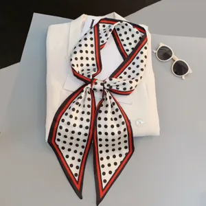 Chic black and white polka dot scarf with red border, versatile long ribbon for neck or hair.