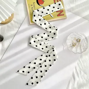 Inquadratura di dettaglio di elegante foulard stretto a pois bianchi e neri, nastro chic.