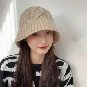 Detail view of a cozy beige chunky cable knit bucket hat, soft winter warm fisherman cap.