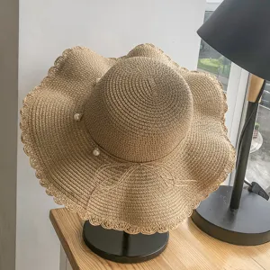 Detailed view of the summer straw sun hat featuring a wavy brim, pearl charm, and delicate bow.