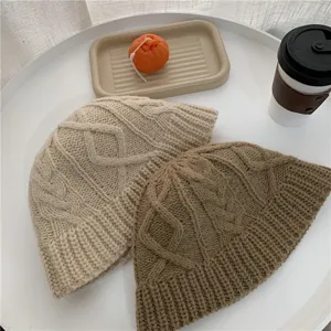 Detailed shot of cozy chunky knit winter beanies in beige and brown with chic cable patterns.