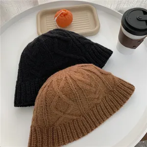 Detailed shot of chunky knit bucket hats in black and brown, cozy winter fashion accessory.