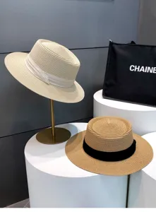 Details of the elegant vintage straw boater hat set with ribbon decoration on display stand.