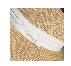 Primo piano dettagliato della texture del cappello di paglia estivo con nastro bianco.