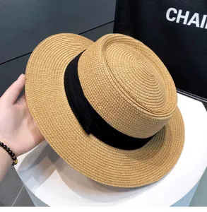 Close-up detail of women summer straw boater hat with black ribbon, elegant vintage style.