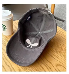 Detail view of dark grey baseball cap with sweet inner bow embroidery and brand tag.
