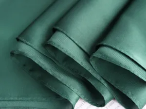 Dark green satin small square scarf detail, showing smooth texture and delicate edges.