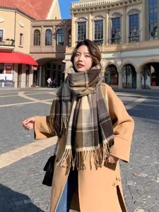 Outdoor street scene detail of a cozy winter plaid scarf with fringe, stylish and warm wear.