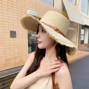 Detailed view of women's straw sun hat with fringe edge, flat top and stylish brown belt decor.