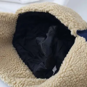 Detail view of winter plush trapper hat interior, warm black lining and soft beige fleece texture.