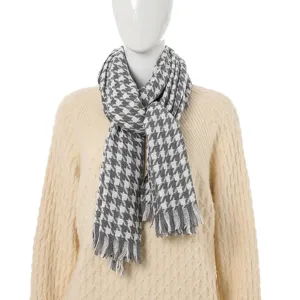 Close-up detail of the classic houndstooth pattern and fringe trim on a winter scarf.