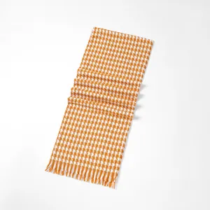 Detailed view of the orange and white houndstooth scarf with fringe texture and soft knit.