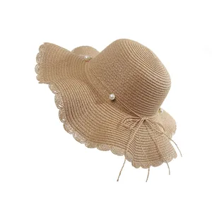 Women's summer straw hat with wavy brim, elegant pearl decor, and bow. Ideal for beach vacation.