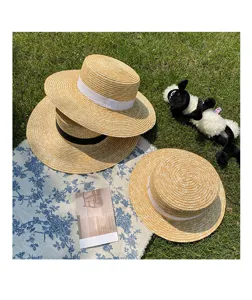 Detail view of stylish flat top straw hat with ribbon, perfect for summer beach sun protection.