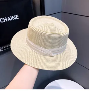Beige flat top straw hat detail, elegant woven sunhat texture, summer vacation beach wear style.
