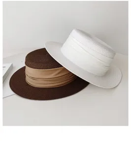 Close-up details of French flat top straw hats in white and brown with wide ribbons.