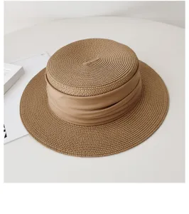 Close-up detail of the woven straw hat surface and elegant khaki ribbon band decoration.
