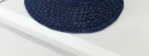 Close-up detail of dark blue denim bucket hat, showing soft washed fabric texture and wide brim.