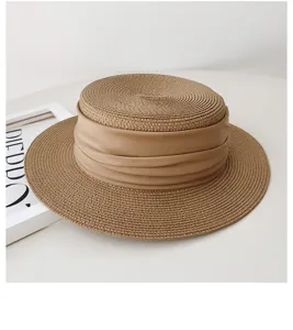 Detailed view of a chic khaki flat top straw hat with stylish draped band accessory for women.