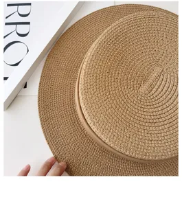 Close-up detail of the textured straw weave and flat brim of a chic summer sun hat.