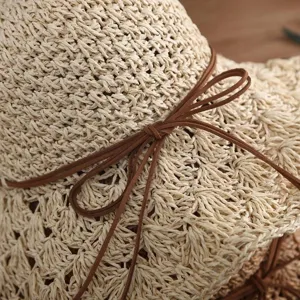 Vue detaillee d'un chapeau de paille beige fait main avec un elegant noeud en daim marron.