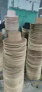 Detail view of large stack of flat top straw hats in factory workshop, summer beach sun hat.