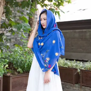 Detail view of ethnic style blue embroidered linen shawl with delicate floral patterns.